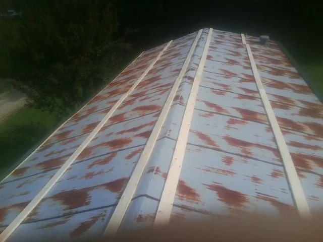 Rusted metal roof panels with new wood purlins before replacement — Storm Damage Roof Repair in Malone by Roofing Brothers
