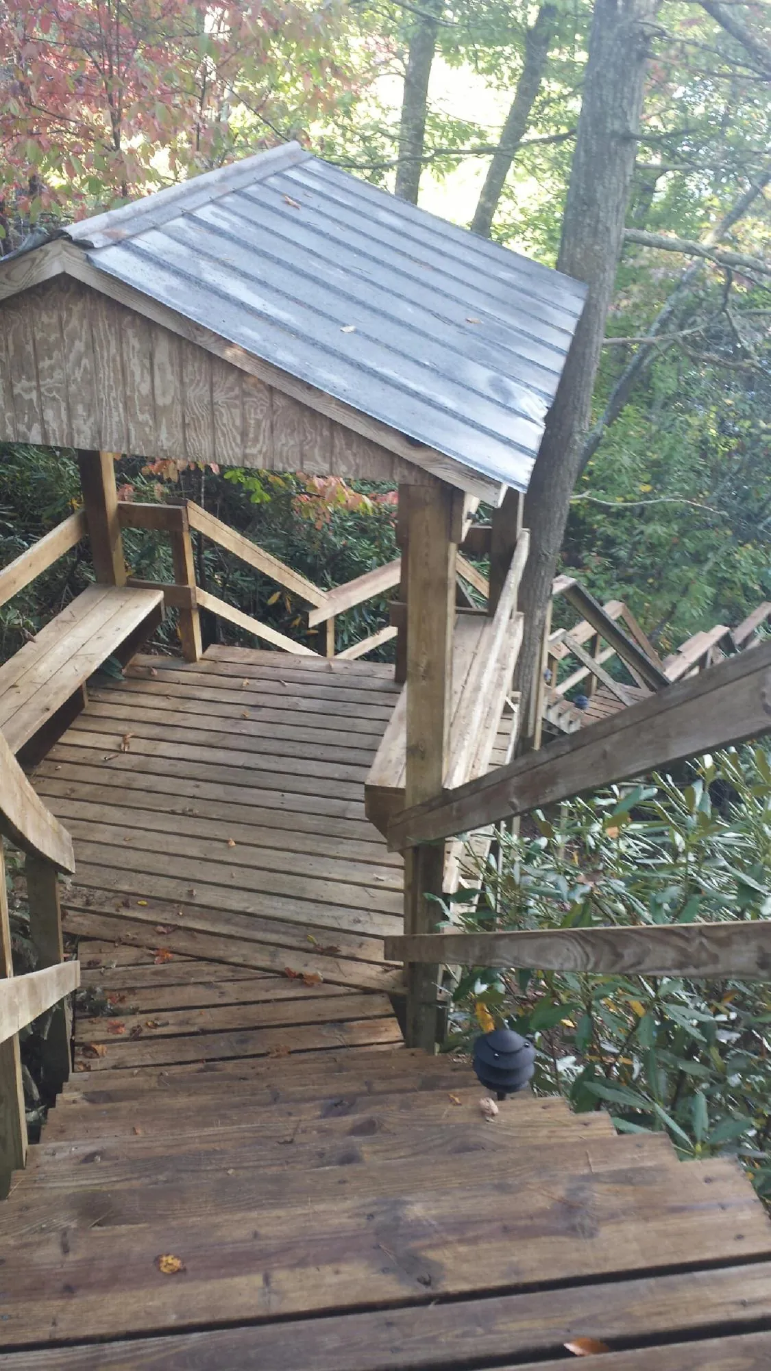 Metal roofed shelter over wooden steps on a wooded walkway — Skylight Repair & Installation work by our crew in Malone