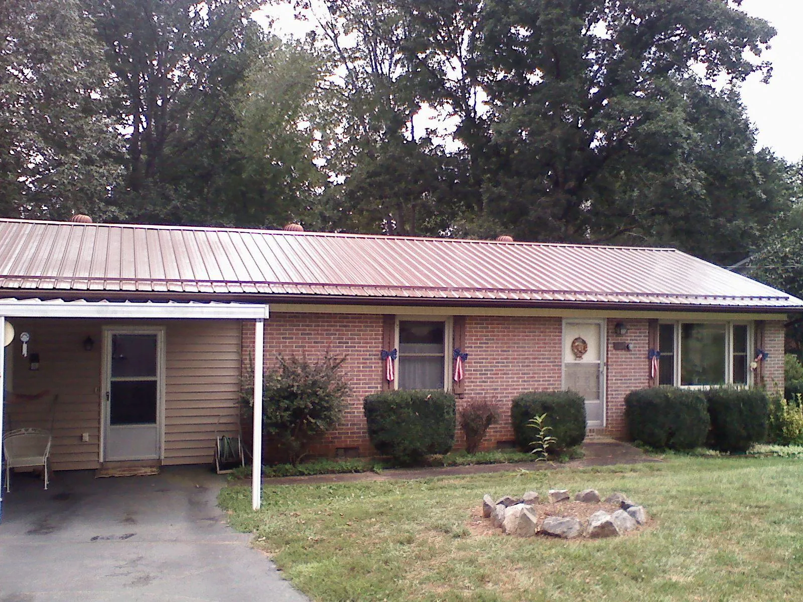 Bronze metal roof and carport on a brick ranch home — Roof Repair work by our crew in Malone